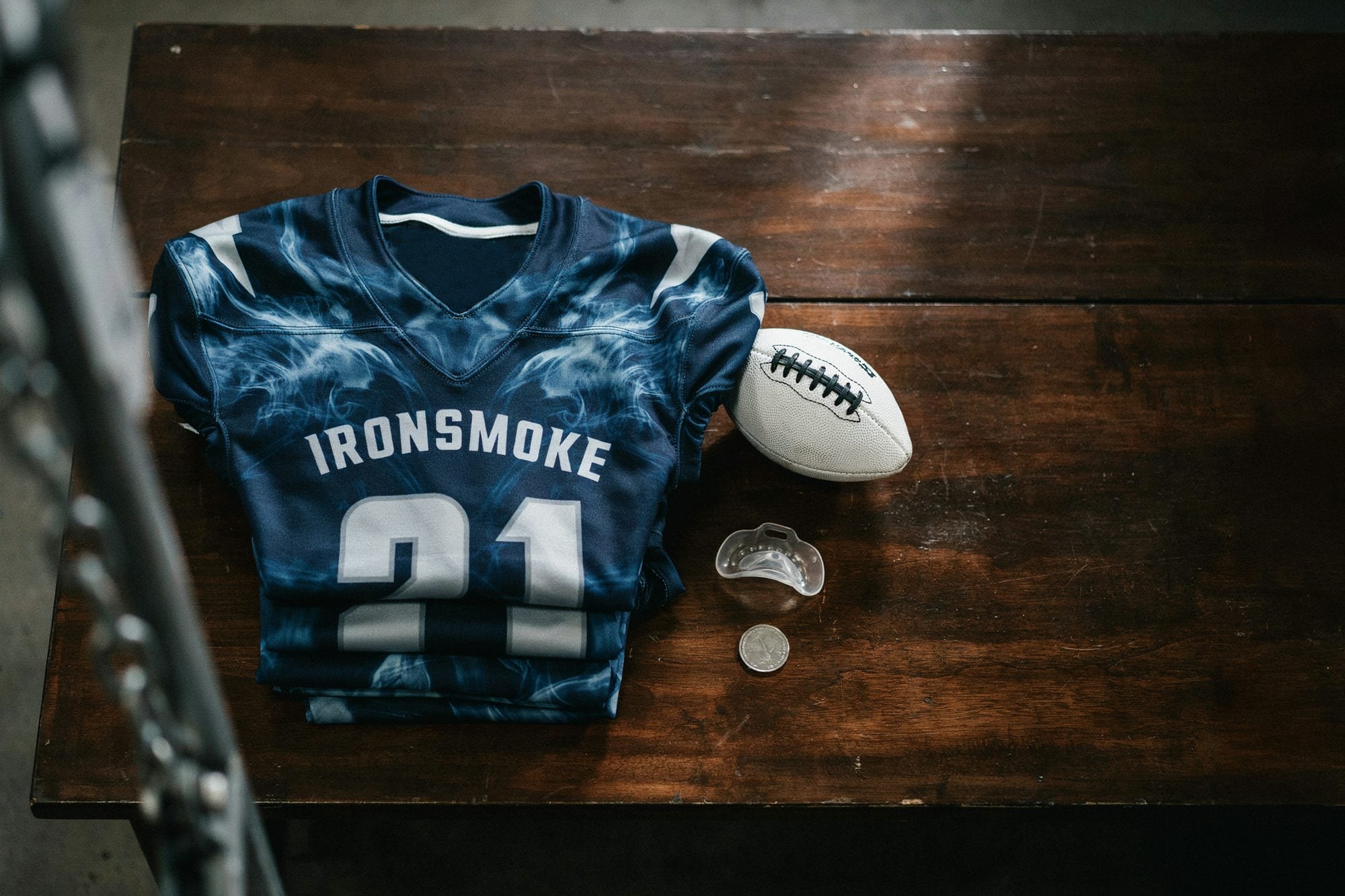A custom navy and silver smoke pattern football jersey laid out with a football and a mouthguard